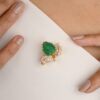 Gold-plated brooch pendant featuring a carved emerald stone