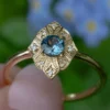 Sterling silver ring featuring pave-set CZ accents and a teal sapphire