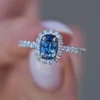 Blue sapphire engagement ring with prong-set CZ side stones