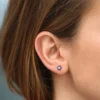 Flower stud earrings featuring a round sapphire and halo style diamonds