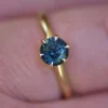 Silver engagement ring with six-prong teal sapphire style setting