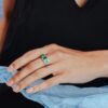 Three stone ring featuring a prong-set emerald centre and CZ diamonds